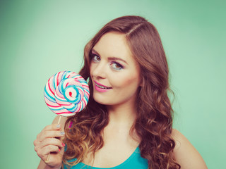 Smiling girl with lollipop candy on teal