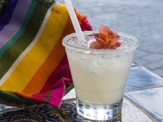 Margarita with salt rim and floating decorative flower with mexican napkin in background