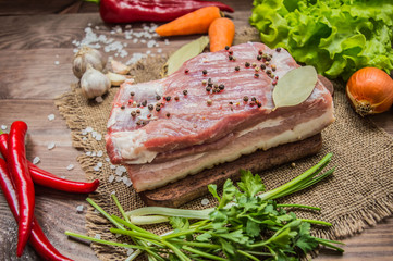 Raw bacon with herbs on a wooden table. Top view. Close-up