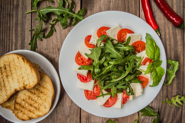 Arugula Salad - Caprese . Wooden background. Top view. Close-up