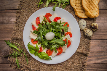 Arugula Salad - Caprese . Wooden background. Top view. Close-up