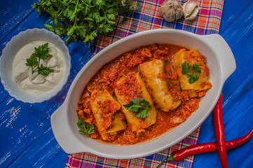 Dinner with cabbage rolls in tomato sauce decorated  parsley. Wooden blue rustic background. Top view. Close-up