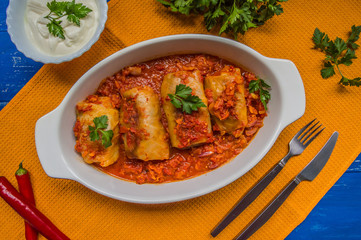 Dinner with cabbage rolls in tomato sauce decorated  parsley. Wooden blue rustic background. Top view. Close-up