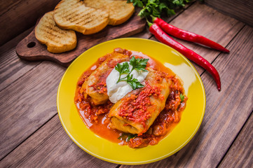 Dinner with cabbage rolls in tomato sauce decorated  parsley. Wooden rustic background. Top view. Close-up