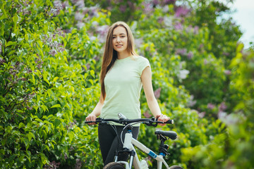 Fototapeta na wymiar Happy young girl cyclist standing with a mountain bike and. Adventure travel. Girl cyclist. Mountain bike. healthy lifestyle. Sort concept.