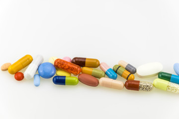 Many colored tablets and capsules isolated on white background.
