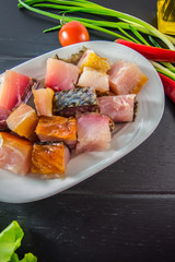 Smoked silver carp to beer on a white plate with greens. Top view. Black background of wood. Close-up