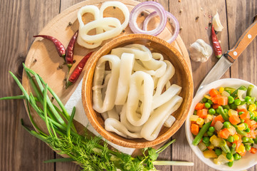 Fresh squid rings and vegetables on a wooden table. top view. Close-up