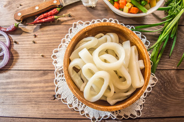 Fresh squid rings and vegetables on a wooden table. top view. Close-up