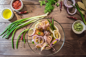 Ready fresh squid rings and tentacles of an octopus with stewed potatoes  greens in rustic. top view. Close-up
