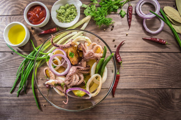 Ready fresh squid rings and tentacles of an octopus with stewed potatoes  greens in rustic. top view. Close-up
