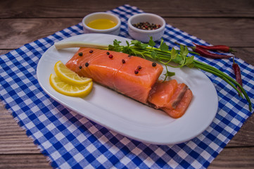 Salmon steak, butter, pepper, lemon and greens on a plate  wooden rustic background. close-up.
