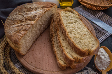 Freshly baked bread and baking ingredients. On a black wooden table.    . Close-up