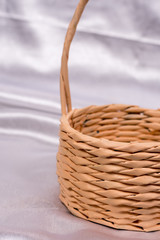 Woven basket for flower arrangement over white satin. Beautiful