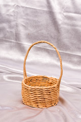 Fototapeta na wymiar Woven basket for flower arrangement over white satin. Beautiful