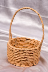 Woven basket for flower arrangement over white satin. Beautiful