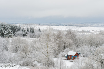 Snowy landscape with wooden house. Winter forest and sky. Beautiful natural background with snow covered trees