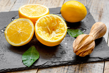 cut oranges in half and juicer on wooden background