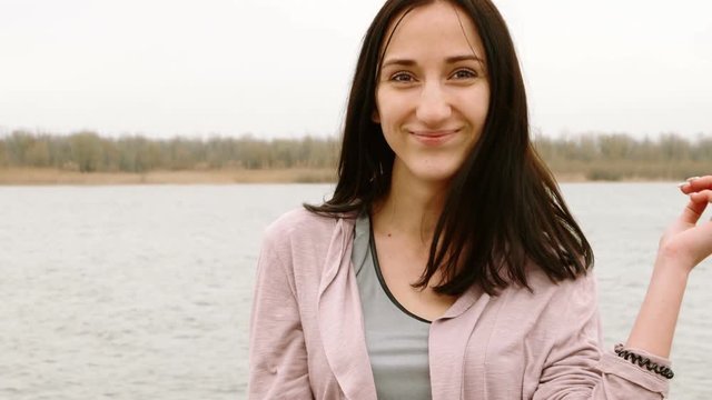 Portrait of cute woman posing by the river side wearing knited jacket