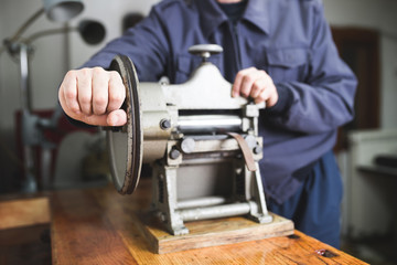 Close up shot of worker's hands in leather belt making process. 
