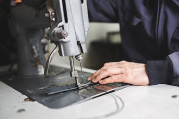 Close up shot of worker's hands in leather belt making process. 