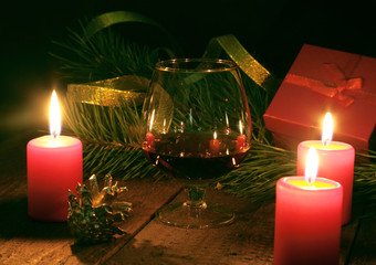 Brandy glass and candles on black background