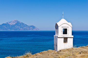 Fototapeta na wymiar Small white church or chapel with holy mount Athos in background, Greece