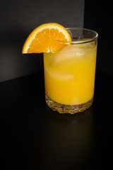 Glass of orange juice on black background