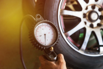 Close up mechanic inflating tire and checking air pressure with gauge pressure              