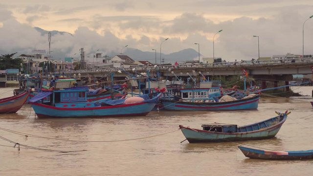 Vietnamese boats on a river at sunset. Busy bridge with lots of motorbikes. Nha Trang, Vietnam travel landscape and destinations.