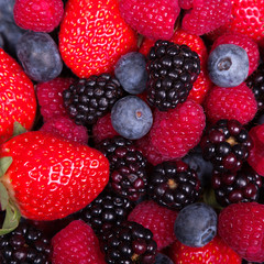 Mixed ripe sweet berries background. Blueberries raspberries, strawberries and blackberries. With space for text.
