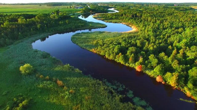 Pristine winding river amid rural wilderness, woodlands.
