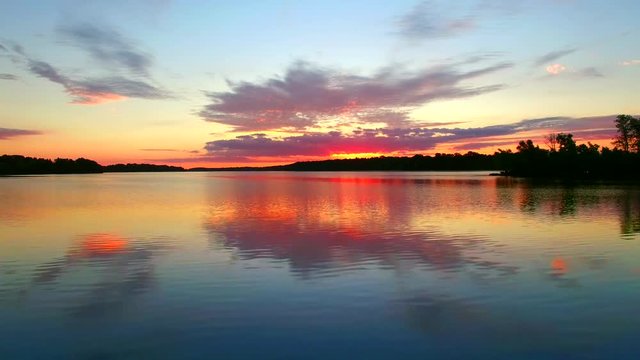 Amazing red sunrise reflected in calm waters, a bass jumps with perfect timing.
