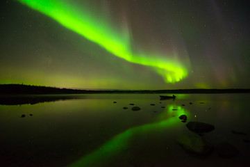 Aurora Borealis and Starry Sky - Multi-colored aurora borealis bright up the starry night sky above a quiet lake.