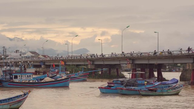 Vietnamese boats on a river at sunset. Busy bridge with lots of motorbikes. Nha Trang, Vietnam travel landscape and destinations.