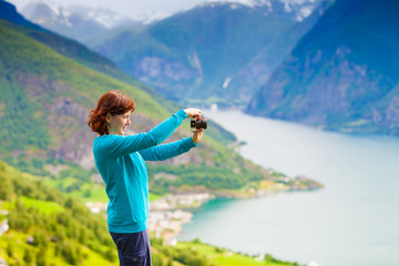 Fototapeta na wymiar Female tourist taking photo at norwegian fjord