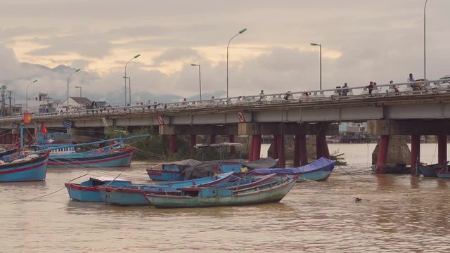 Vietnamese boats on a river at sunset. Busy bridge with lots of motorbikes. Nha Trang, Vietnam travel landscape and destinations.