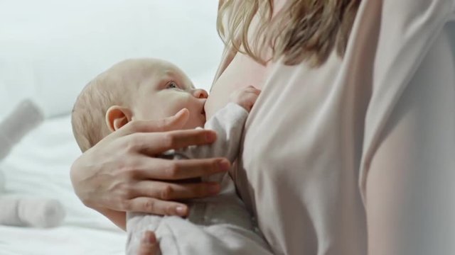 Slow motion of little baby boy sucking on mothers breast 