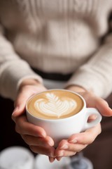 holding hot cup of coffee, with leaf shape