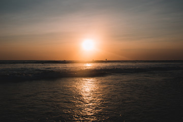 Fototapeta na wymiar Sunset on the beach of Indian ocean with surfers, Indonesia, Bali