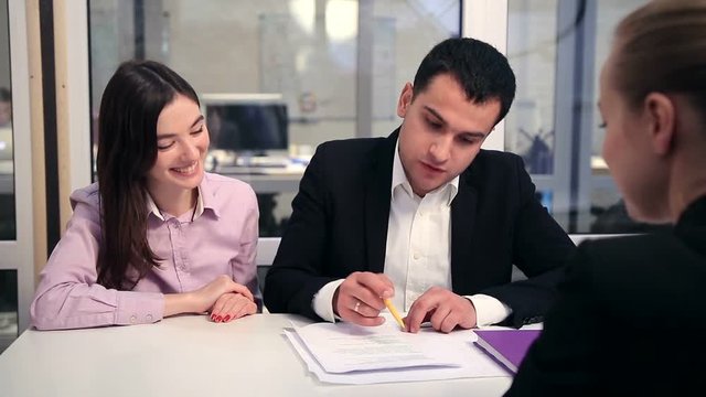 Smiling couple signing home purchase agreement