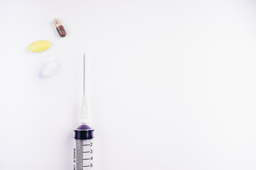 Medication in tablets and capsules and insulin syringe on white  background,Empty syringe