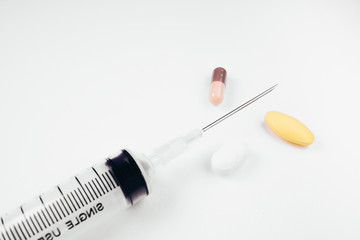 Medication in tablets and capsules and insulin syringe on white  background,Empty syringe