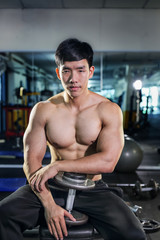 Fototapeta na wymiar Handsome asian man with dumbbell in the gym