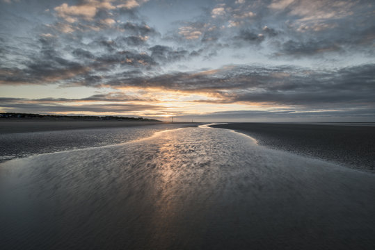 Beautiful beach coastal low tide landscape image at sunrise with