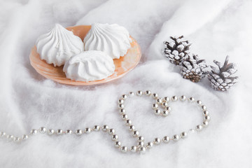 Airy zephyrs in the dish on the soft cloth with a cones and decorative, small balls chain in heart form. In special moment like Christmas evening.. Romance. Very beautiful.