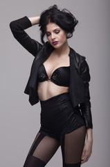 Sensual slim brunette lady posing in black sexy lingerie. Long curly hair.