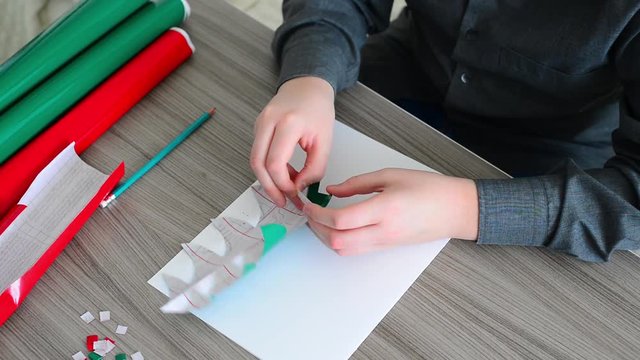 Teen Boy making Christmas card from color paper