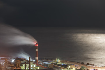 Factory against the sea in the moonlight