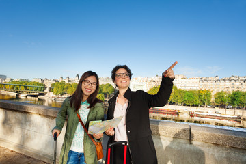 Happy friends walking along embankment of Seine
